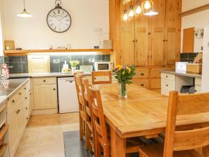 a kitchen with a wooden table and chairs and a clock at Penholm in Penmaen-mawr