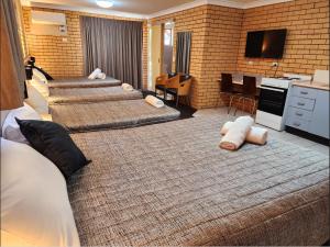 una camera d'albergo con 4 letti e una cucina di Tallarook Motor Inn a Dubbo