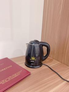 Czarny czajnik do herbaty siedzący na stole obok książki w obiekcie White Crown Hotel w Ha Long