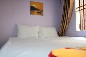 un letto con lenzuola e cuscini bianchi in una stanza di Hiep Tung homestay a Tân Hiệp