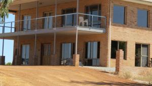 a brick building with a balcony on a dirt road at Turquoise Coast Fishing Lodge in Jurien Bay