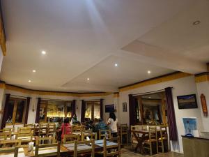 a restaurant with wooden chairs and people sitting at tables at Ratna Hotel Ladakh in Leh