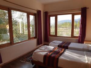 two beds in a room with two windows at Ratna Hotel Ladakh in Leh