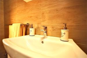 a white bathroom sink with two candles on it at Bacchus Pub és Panzió in Dunaharaszti