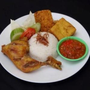 een bord met rijst en groenten en een saus bij SIMPANG 7 RESIDENCE in Kudus