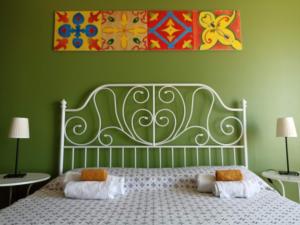 a bedroom with a white bed with a painting on the wall at Good Morning Etna in Bronte