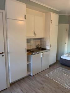 a kitchen with white cabinets and a sink and a bed at Halek Hem - Haga studio in Enånger