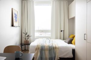 a white bedroom with a bed and a window at Noli Malmi in Helsinki