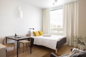 Schlafzimmer mit einem Bett, einem Schreibtisch und einem Fenster in der Unterkunft Noli Malmi in Helsinki