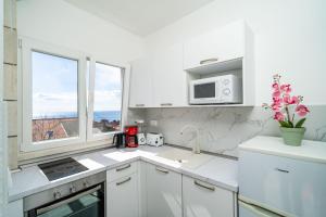 cocina blanca con fregadero y microondas en Apartment Debos, en Dubrovnik