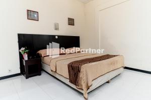 ein Schlafzimmer mit einem Bett in einem Zimmer in der Unterkunft Cherry Pink Hotel Medan Mitra RedDoorz in Medan