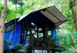 a blue building with a staircase in a forest at Hau Eco Lodges Citumang Pangandaran in Pangandaran