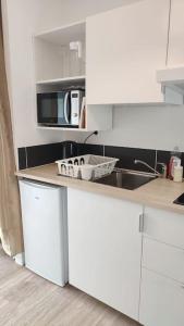 a white kitchen with a sink and a microwave at Studio calme et discret in Brest