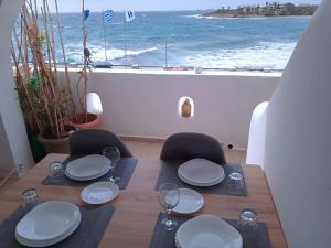 a table with plates and glasses and a view of the ocean at Logaras Seaview Apartment in Logaras
