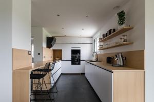 cocina con armarios blancos y suelo negro en Villa L'Oliveraie - Belle maison pour 6, en Lavilledieu
