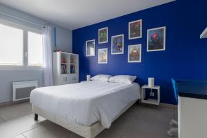 Un dormitorio azul con una cama grande y una pared azul en Villa L'Oliveraie - Belle maison pour 6, en Lavilledieu