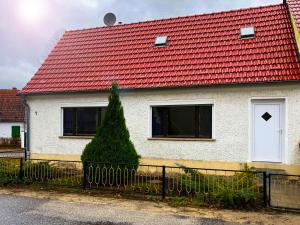 a white house with a red roof with a fence at Ruhige Monteurwohnung in Werder in Plötzin