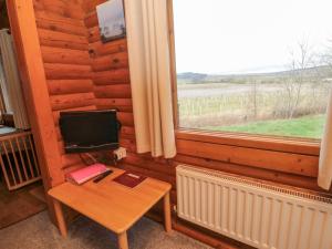 a room with a small table with a television and a window at Glanton in Morpeth