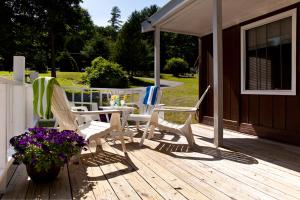 a deck with chairs and a table and flowers at Rock Castle Resort in Lake George