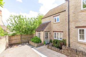 een stenen huis met een hek ervoor bij Oxfordshire Living - The Henrietta Cottage - Woodstock in Woodstock