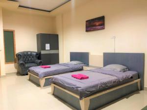 1 dormitorio con 2 camas y 1 silla en MS Hotel Pinrang Mitra RedDoorz, en Pinrang