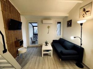 sala de estar con sofá negro y mesa en Studio azur, en Aigues-Mortes