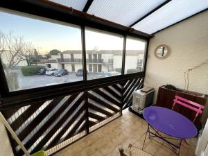 Un balcón con una silla púrpura y una ventana en Studio azur, en Aigues-Mortes
