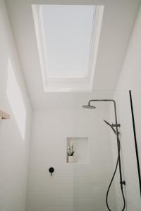 a white bathroom with a shower with a skylight at View Street Studios - Tallerack in Albany
