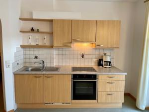 a kitchen with wooden cabinets and a sink at Residence Feldhof in Kastelbell-Tschars