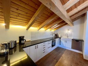 a large kitchen with white cabinets and wooden ceilings at Chalet Alpenflair in Pfronten