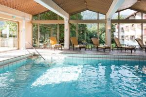 a large swimming pool with chairs and a table at Alpenhof in Bayrischzell