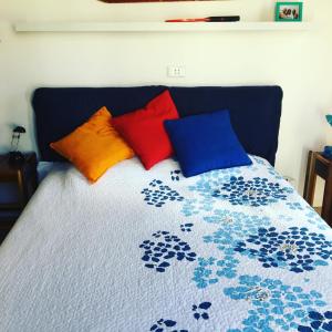 Una cama con 4 almohadas de colores. en Mari & Popi’s House, en Mestre