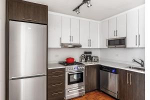 a kitchen with white cabinets and a stainless steel refrigerator at Chelsea 1BR w Gym Concierge nr Penn Stn MSG NYC-439 in New York