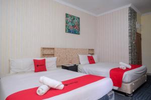 una camera d'albergo con due letti con lenzuola rosse e bianche di RedDoorz at Mamagayo Inn Yogyakarta a Yogyakarta