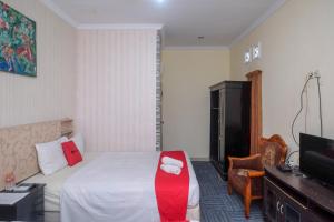 una camera d'albergo con letto e sedia rossa di RedDoorz at Mamagayo Inn Yogyakarta a Yogyakarta