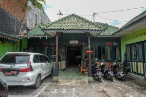 日惹的住宿－RedDoorz at Mamagayo Inn Yogyakarta，一辆停放在一座带摩托车的建筑前的白色汽车