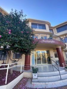 a building with stairs and a tree in front of it at Normandie Wollongong in Wollongong