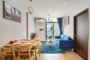 a living room with a table and a blue couch at CSJ Seaside - Căn Hộ Cạnh Biển in Vung Tau