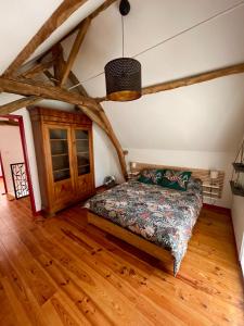 een slaapkamer met een bed in een kamer met houten vloeren bij Maison de campagne, Gîte rouge in Brigné