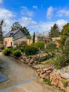 un patio con una casa y un jardín con rocas en Maison de campagne, Gîte rouge, en Brigné