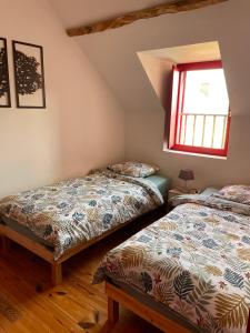 two beds in a room with a window at Maison de campagne, Gîte rouge in Brigné