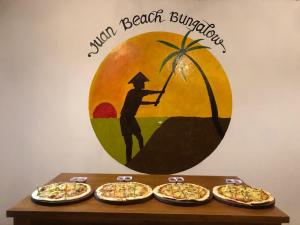Juan Beach Bungalow في نوسا بينيدا: طاولة فيها اربعة بيتزا موضوعة فوقها