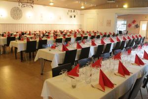 un salón de banquetes con mesas y sillas y servilletas rojas en Hotel Urkin Piilopirtti, en Pinsiö