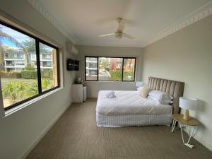 a bedroom with a bed and two large windows at Normandie Wollongong in Wollongong