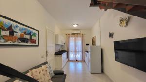 a living room with a couch and a television and a kitchen at Villetta Eliselena Best Vacation Ever in Villasimius +15 photos