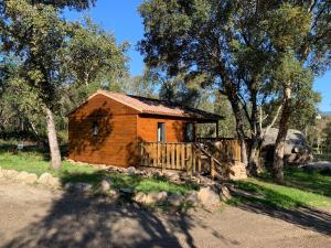 a small wooden cabin with a fence and trees at L'Aravone Lodge in Sartène