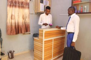 deux hommes debout à un comptoir dans un salon de coiffure dans l'établissement JOEL'S HOTELS & SUITES, à Ikeja