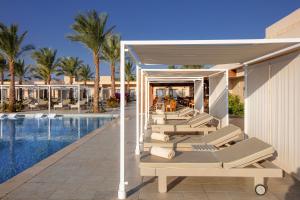 - une rangée de chaises longues à côté de la piscine dans l'établissement Steigenberger Makadi - Adults Friendly 16 Years Plus, à Hurghada