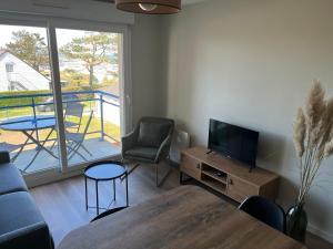 a living room with a couch and a television and a balcony at Le Scottish in Camiers