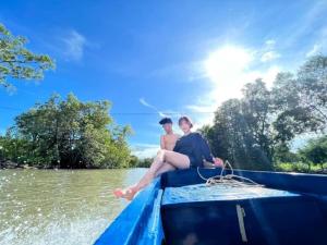 two people sitting on the back of a boat on the water at Homestay Hải Nam Đất Mũi in Xóm Mũi